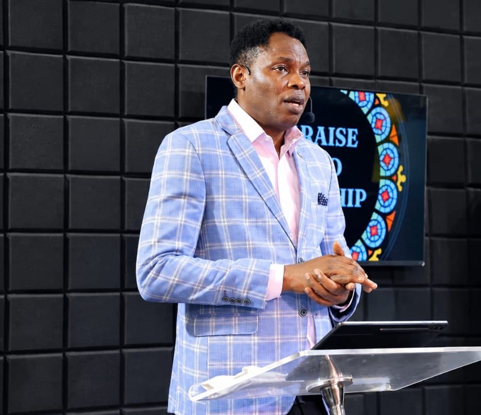 Wole Abraham Martins speaking at a lectern in a blue blazer